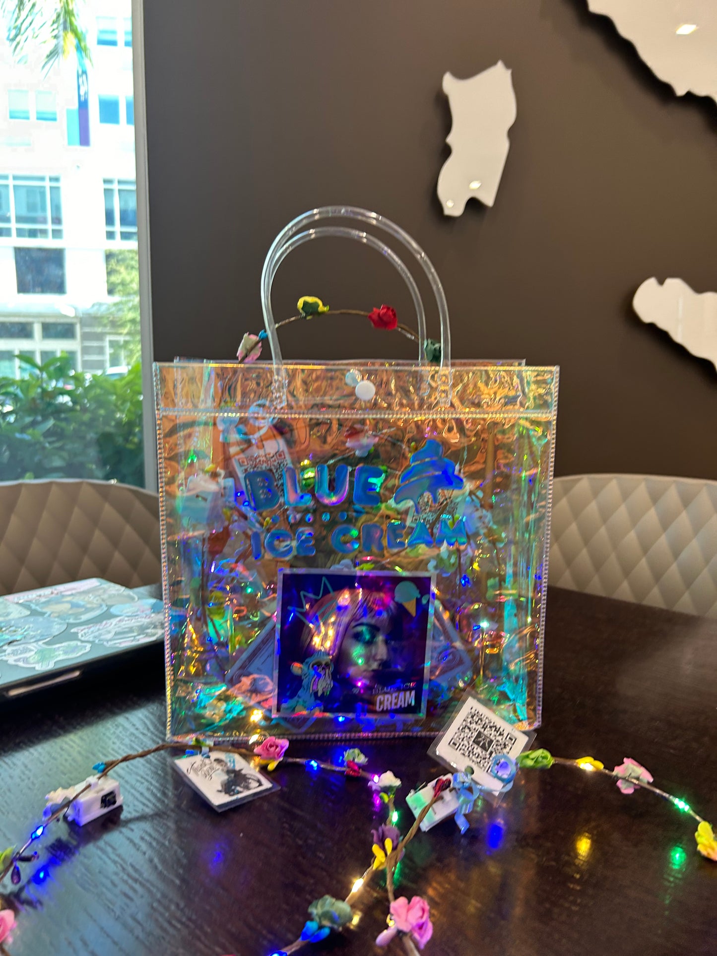 Holographic product on a dark surface with decorative lights and cut-out shapes.