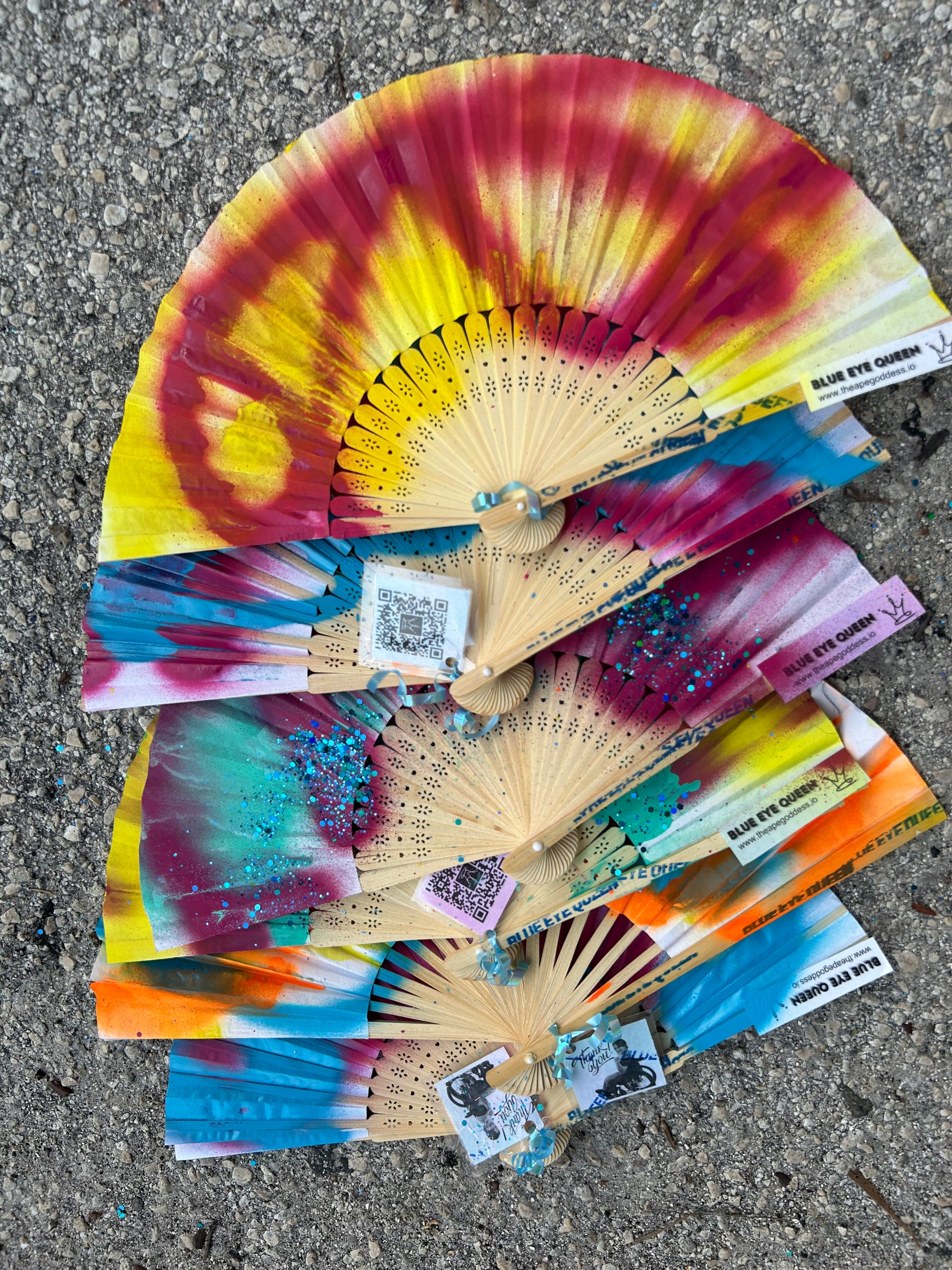A collection of hand-painted fans displayed on a surface, with vibrant multicolored patterns.