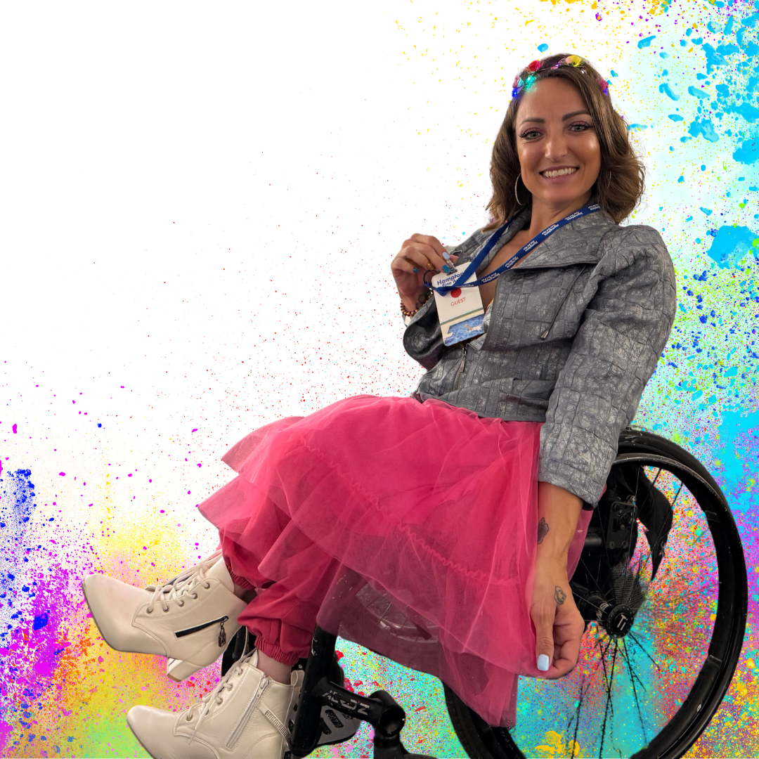 Woman in a wheelchair wearing a pink skirt and gray jacket against a colorful abstract background