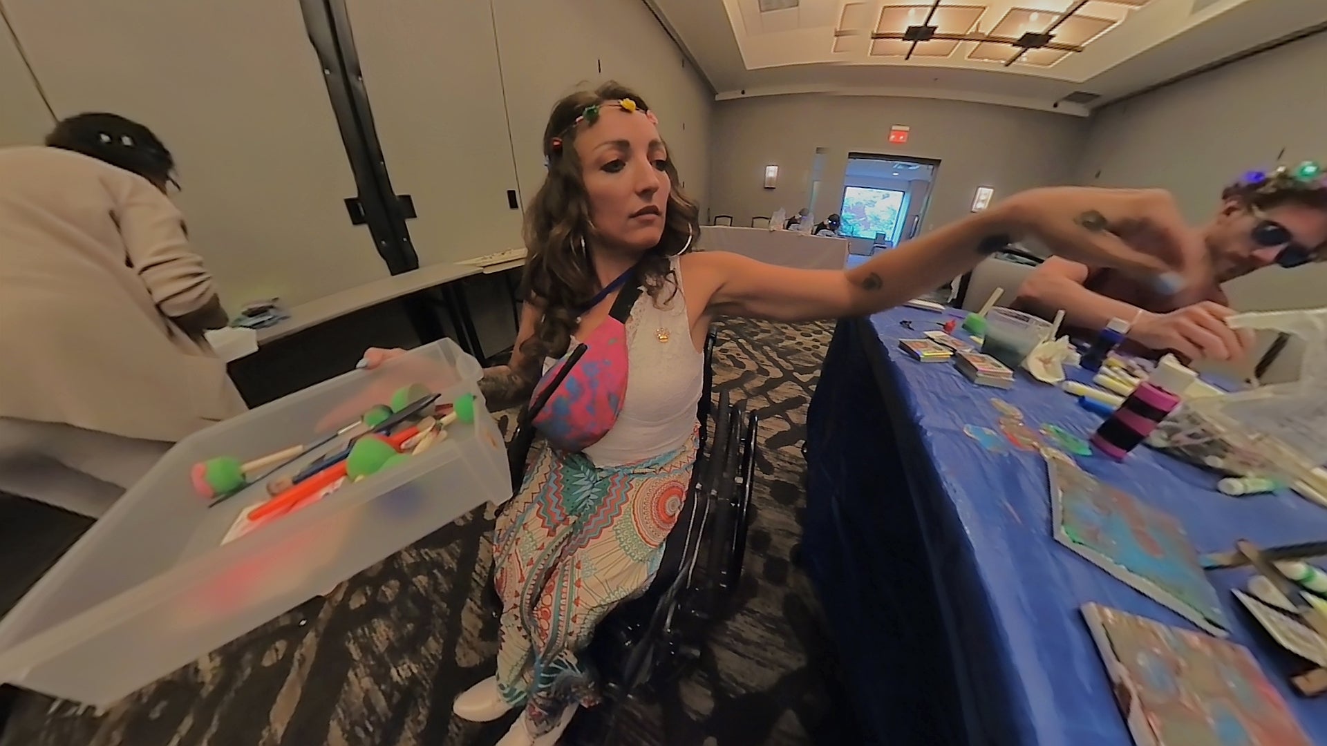 Woman in a wheelchair at a table with art supplies in a room setting